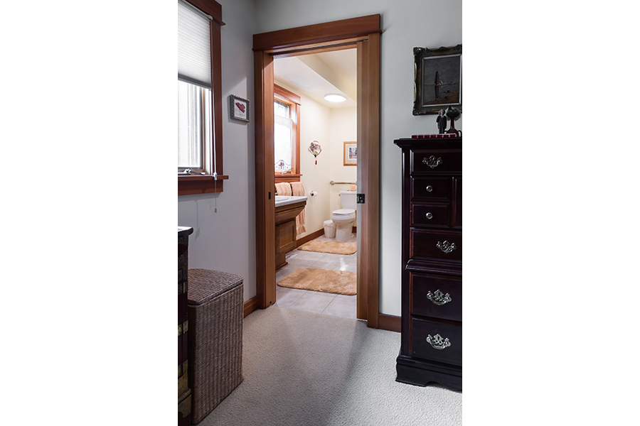 An accessible path of travel leads through a carpeted area into a bathroom on the first floor.